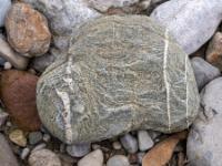 Graubrauner Stein mit Wellenstruktur und weißen Maserungen